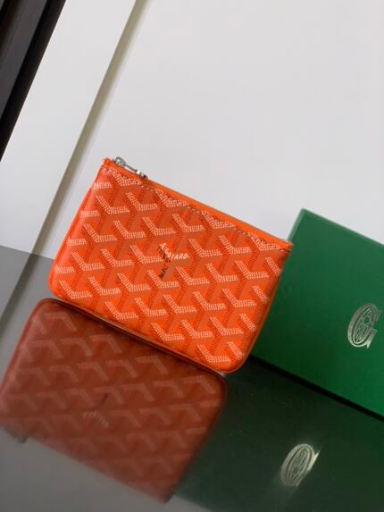 Two wallets in orange and brown colors, next to a green box