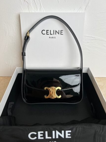 Black glossy handbag with gold metal clasp, inside a brand packaging box