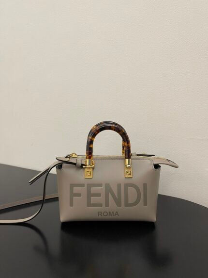 White handbag with tortoiseshell handle, gold hardware, on a black background