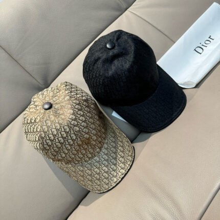 Two hats, one black and one beige with a pattern, placed on a sofa with a box nearby.