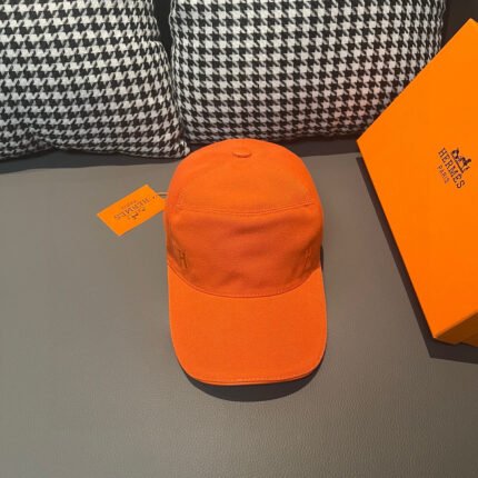 An orange hat with a yellow box and tag, set against a background of black and white checkered cushions.