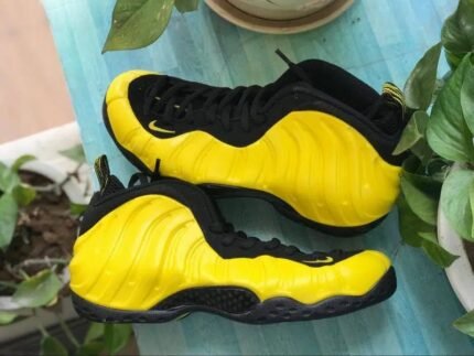 A pair of yellow sports shoes with black details and a black sole